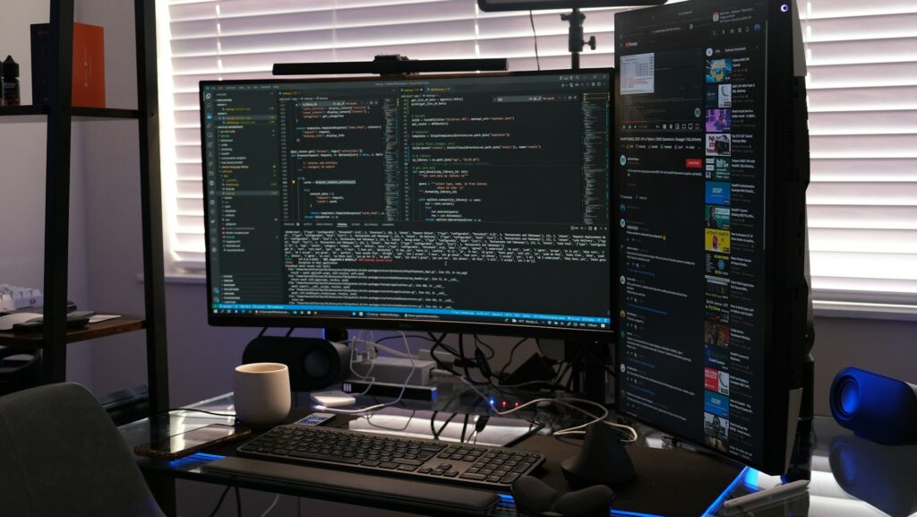 A computer screen displaying multiple windows, set on a desk with various electronic devices, including a keyboard and monitor, in an office environment.