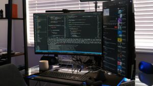 A computer screen displaying multiple windows, set on a desk with various electronic devices, including a keyboard and monitor, in an office environment.