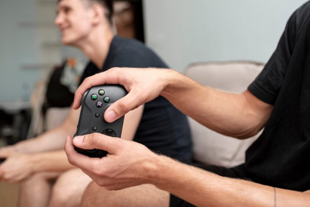 A person holds a game controller, intensely focused while gaming with a friend in a cozy living room setting.