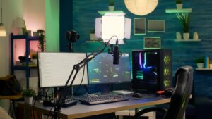 A modern gaming setup featuring dual monitors, a microphone on an arm, a camera, and colorful LED lights in a cozy room.
