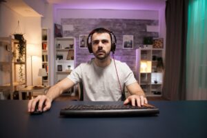 A person wearing headphones sits at a computer desk, focused on the screen in a stylish, well-lit room surrounded by decor.