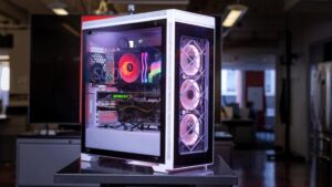 A sleek gaming PC with RGB lighting, showcasing a powerful GPU and multiple cooling fans, set in a modern office environment.