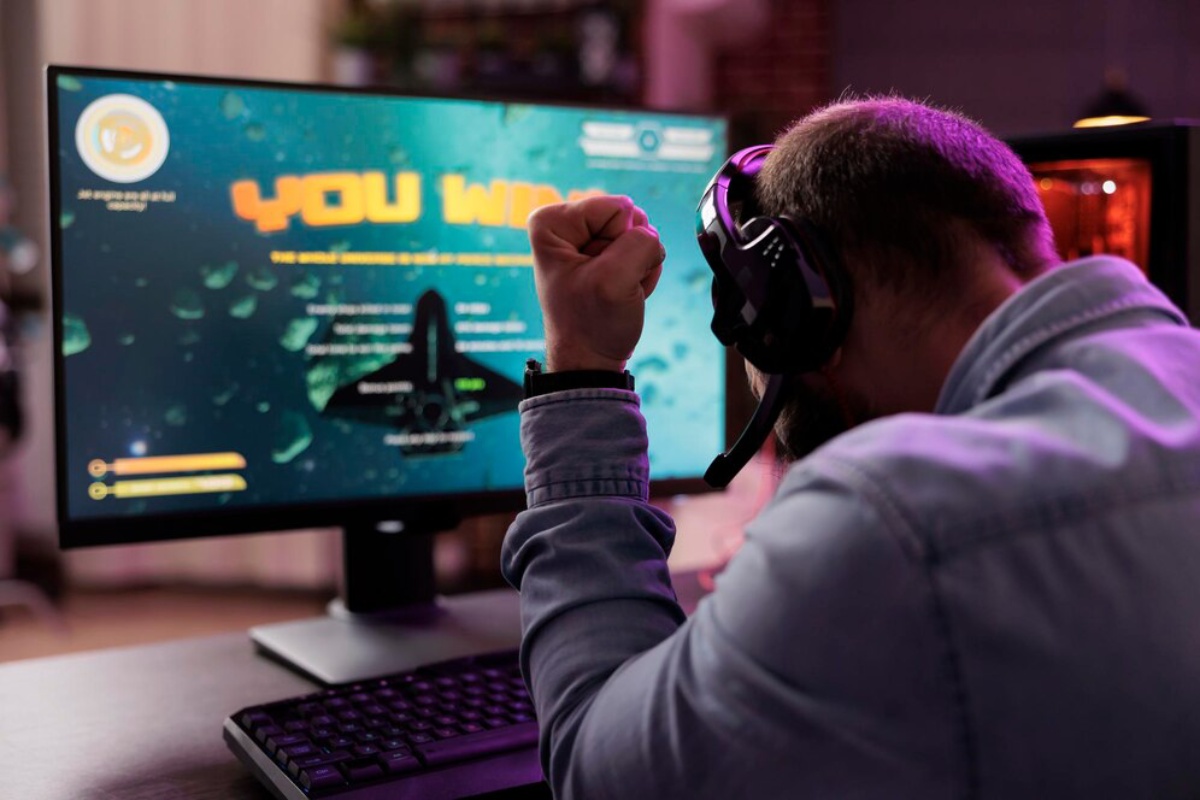 A gamer celebrating a victory with a raised fist, wearing a headset, in front of a monitor displaying 