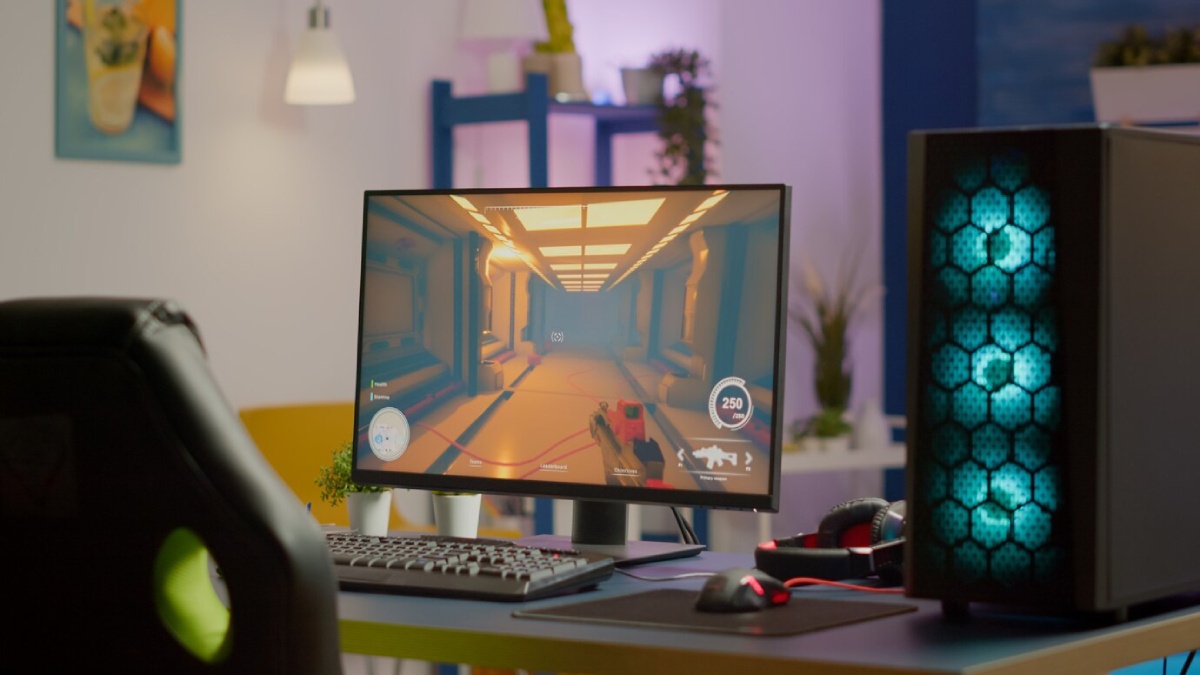 A gaming setup featuring a monitor displaying an indoor game scene, with a keyboard, mouse, and a stylish PC tower with blue lighting.