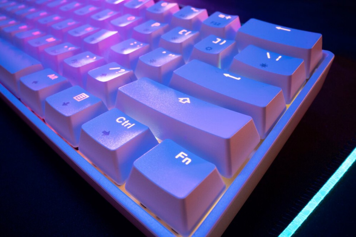 Close-up of a backlit mechanical keyboard with vibrant blue and pink lighting, showcasing illuminated keys and smooth texture.